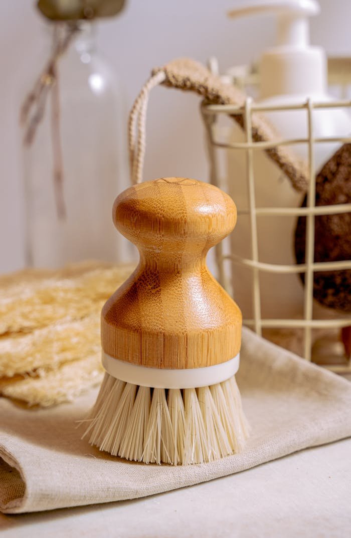 hero-img-01 Close-up of a bamboo scrub brush with eco-friendly bath essentials on a bathroom countertop.