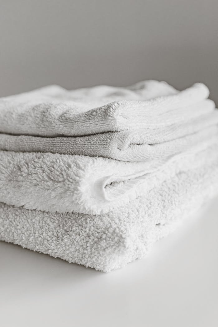 about-01 Neatly folded clean white towels stacked on a surface, perfect for home or spa use.